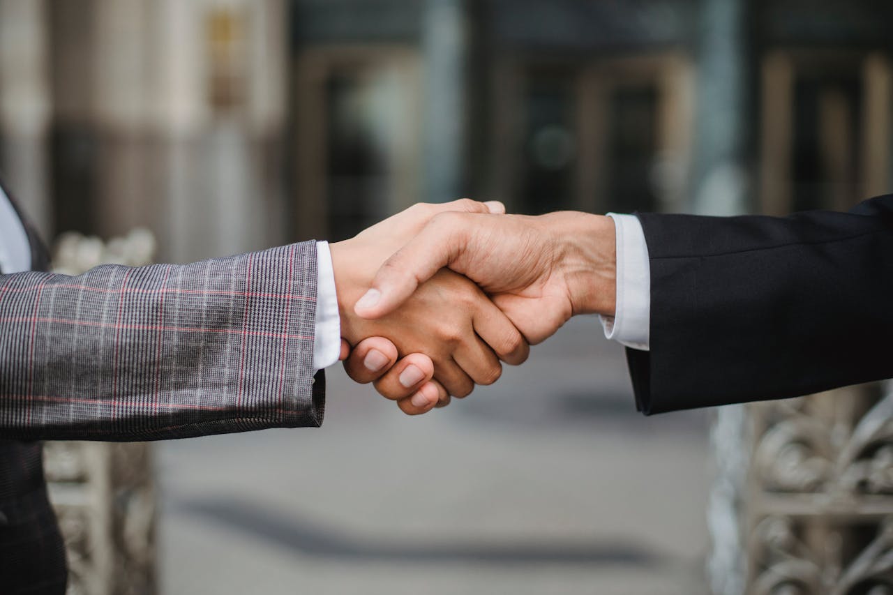 Close-up of two business professionals shaking hands outdoors, symbolizing agreement, partnership, or successful negotiation.